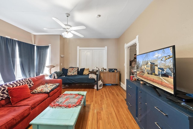 living area featuring baseboards, light wood-type flooring, and ceiling fan