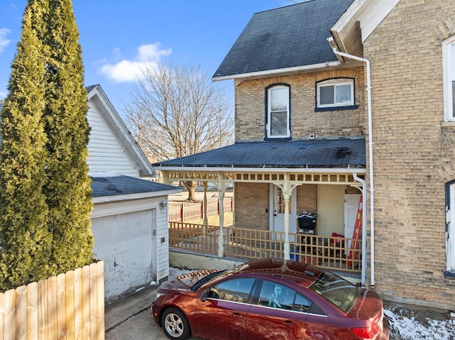 view of front of property with fence, roof with shingles, covered porch, a garage, and brick siding