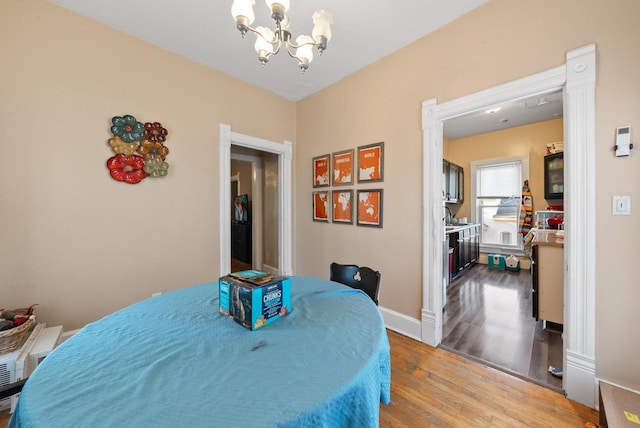 dining area with baseboards, light wood-style floors, and a chandelier