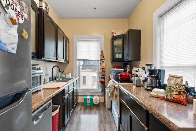 kitchen with dark wood-style floors, stainless steel appliances, glass insert cabinets, and a sink