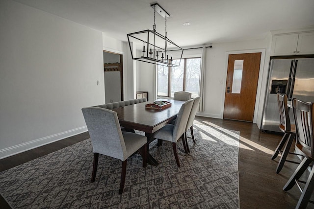 dining room featuring dark wood-type flooring, a notable chandelier, and baseboards