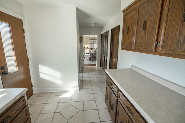 kitchen with light tile patterned floors, brown cabinets, light countertops, and baseboards