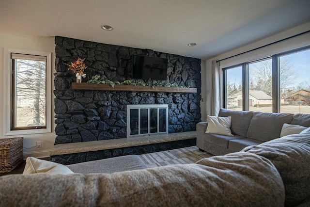 living room with a stone fireplace and a healthy amount of sunlight