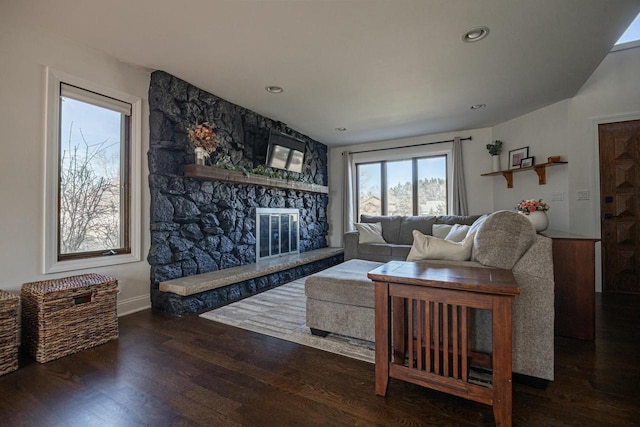 living area with a stone fireplace, recessed lighting, baseboards, and wood finished floors