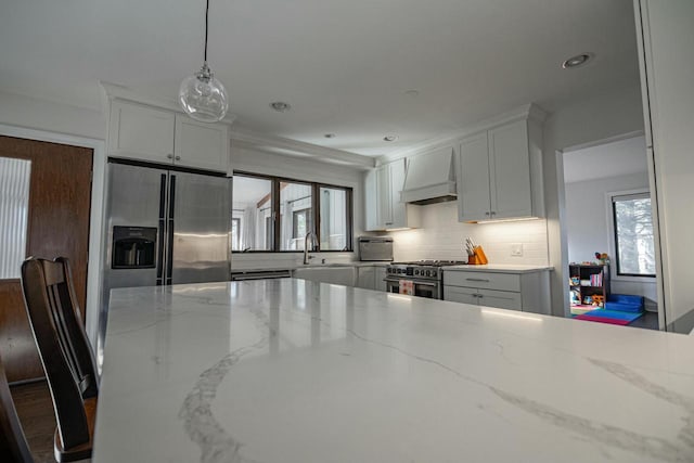 kitchen featuring light stone countertops, custom exhaust hood, a sink, appliances with stainless steel finishes, and backsplash