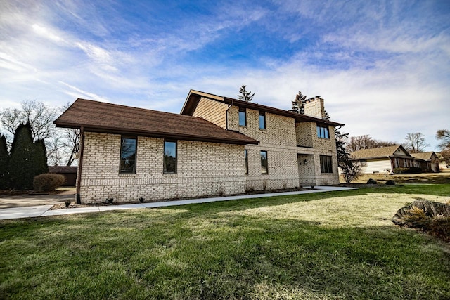 back of house with a lawn, brick siding, and a chimney