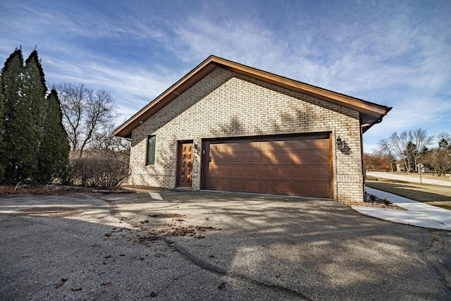 view of home's exterior featuring brick siding, an attached garage, and aphalt driveway