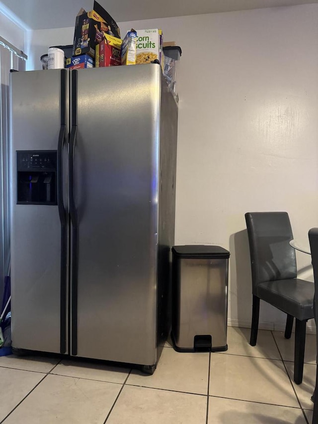 interior space featuring light tile patterned flooring and stainless steel fridge with ice dispenser