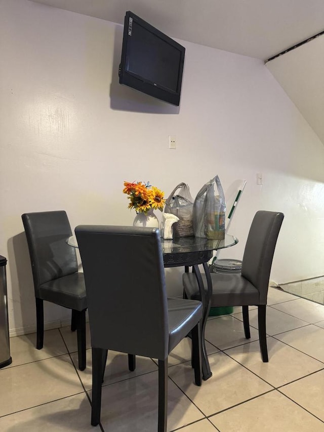 dining room featuring light tile patterned floors and vaulted ceiling