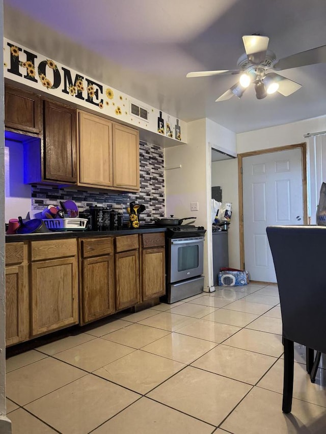 kitchen with light tile patterned floors, backsplash, dark countertops, and stainless steel range with electric cooktop