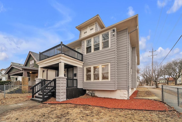 view of front of house with a balcony, covered porch, and fence