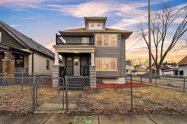 american foursquare style home with a balcony, a gate, and a fenced front yard