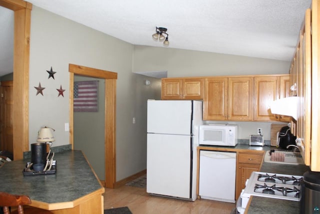 kitchen with a sink, white appliances, dark countertops, and lofted ceiling