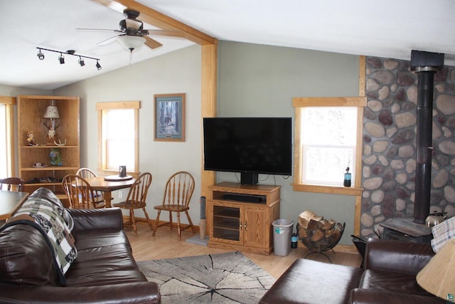 living area with vaulted ceiling, a wood stove, wood finished floors, and a ceiling fan