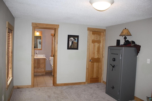 bedroom featuring light carpet, a textured ceiling, and baseboards