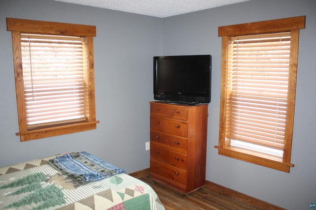 bedroom with a textured ceiling, baseboards, and wood finished floors