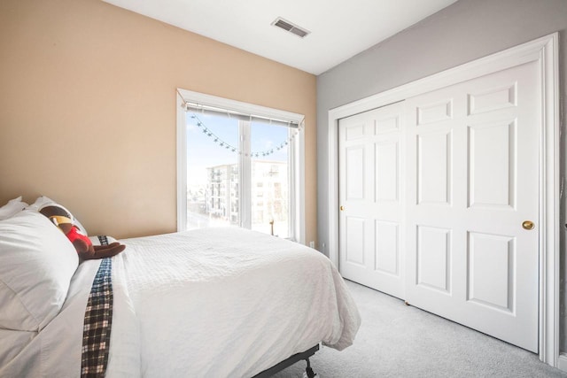 bedroom with light colored carpet, visible vents, and a closet