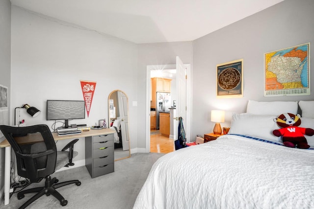 bedroom featuring light colored carpet, ensuite bathroom, baseboards, and stainless steel fridge