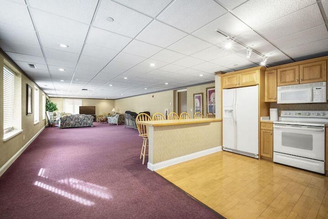 kitchen featuring rail lighting, white appliances, a paneled ceiling, and baseboards