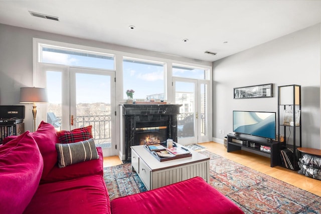 living area with visible vents, wood finished floors, and a glass covered fireplace