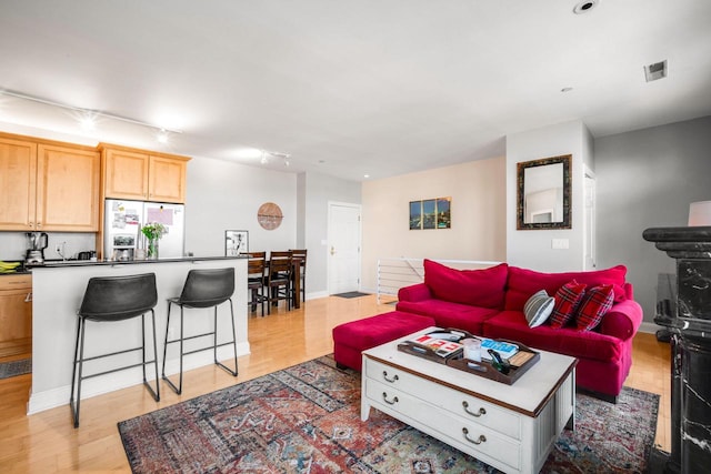 living area featuring light wood-style flooring, baseboards, and visible vents