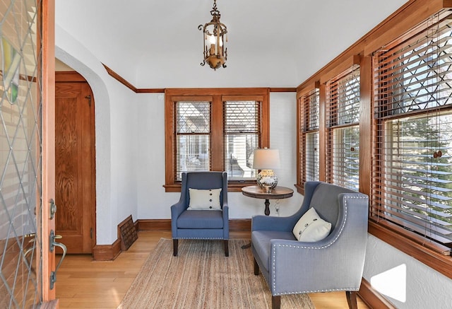 sitting room featuring light wood-style flooring, baseboards, and arched walkways