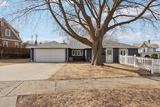 ranch-style house featuring a fenced front yard, concrete driveway, an attached garage, a shingled roof, and a chimney