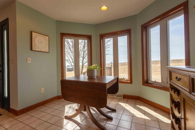 dining area with light tile patterned floors, plenty of natural light, and baseboards