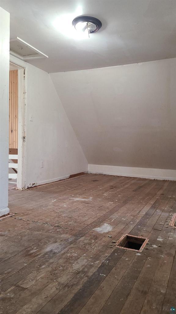 additional living space with hardwood / wood-style flooring and lofted ceiling