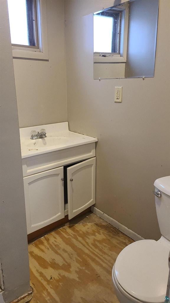 bathroom with a wealth of natural light, toilet, vanity, and wood finished floors