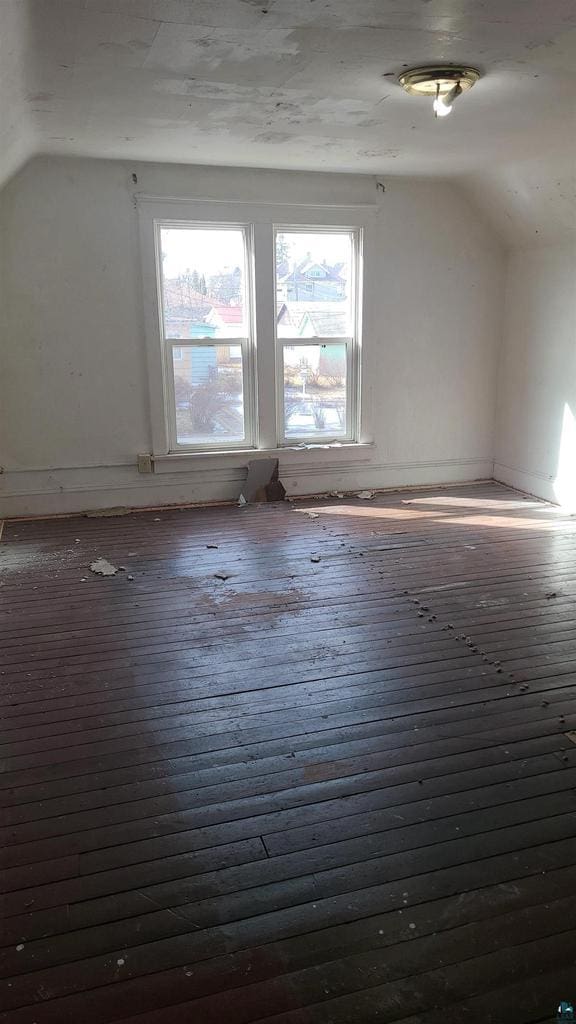 additional living space featuring vaulted ceiling and dark wood-style flooring