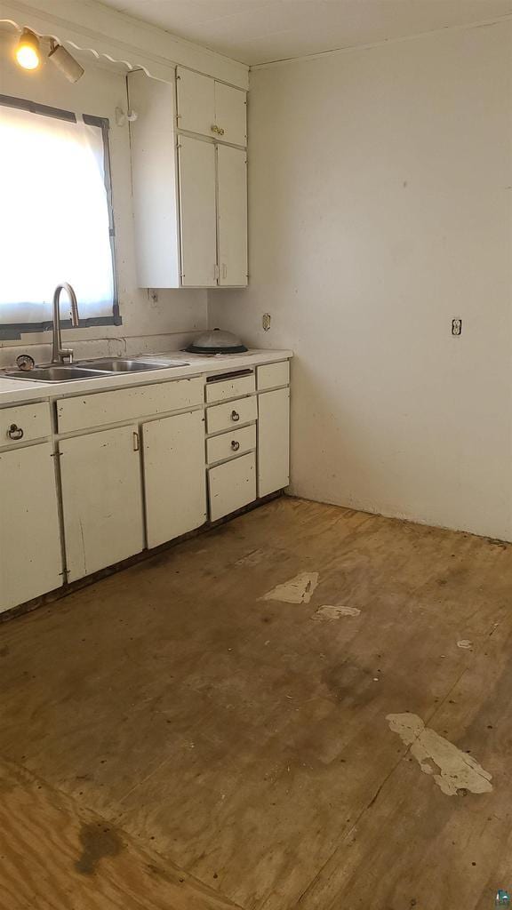 kitchen with a sink, light countertops, and white cabinetry