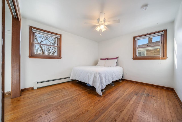 bedroom with hardwood / wood-style floors, a ceiling fan, baseboards, and a baseboard radiator