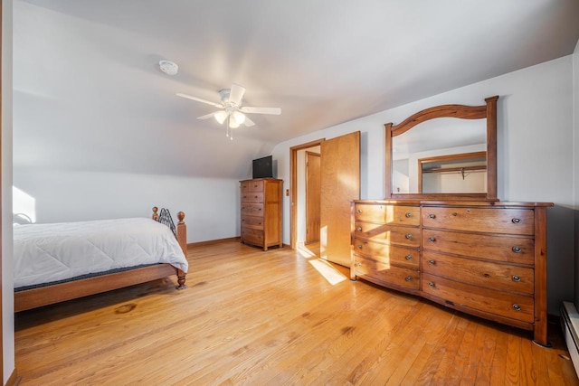 bedroom featuring a baseboard heating unit, light wood-type flooring, ceiling fan, and vaulted ceiling