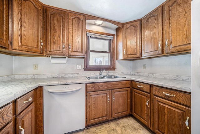 kitchen with light countertops, brown cabinetry, white dishwasher, and a sink