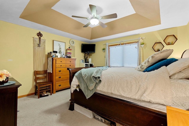 bedroom with a raised ceiling, baseboards, carpet floors, and ceiling fan