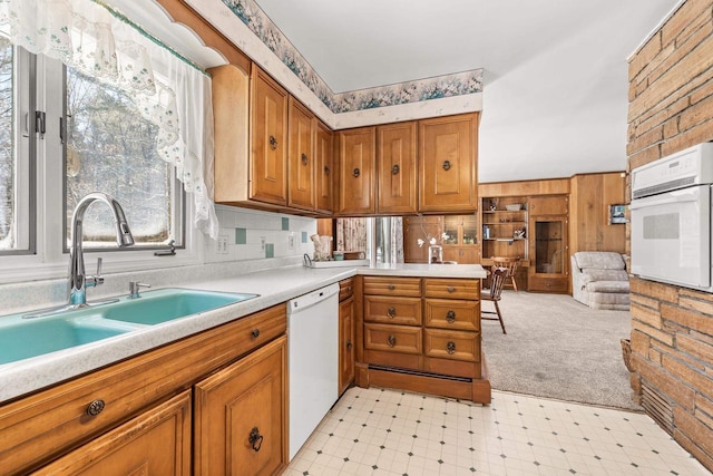 kitchen featuring brown cabinetry, white appliances, light countertops, and a sink