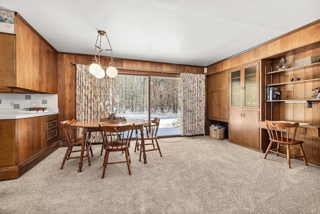 dining area featuring crown molding, wood walls, and light carpet