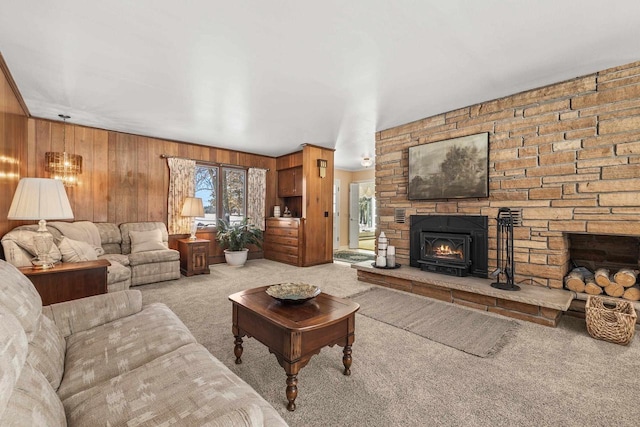 carpeted living area with a stone fireplace and wood walls