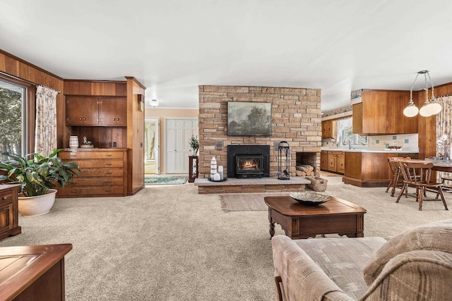 living room featuring a stone fireplace, light colored carpet, and wood walls