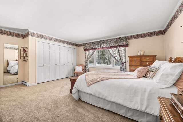 carpeted bedroom with a closet, crown molding, baseboards, and a baseboard radiator