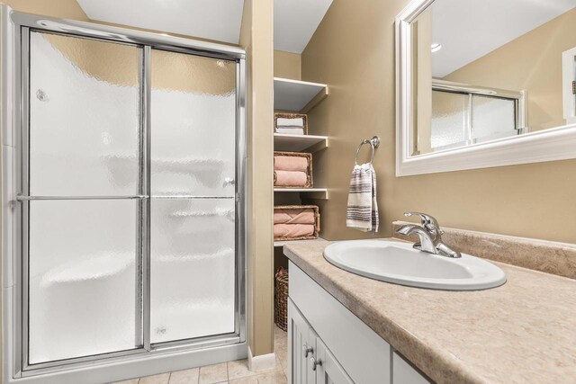 full bathroom featuring tile patterned floors, a stall shower, and vanity