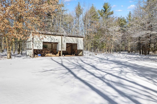 snow covered structure with an outbuilding and an outdoor structure