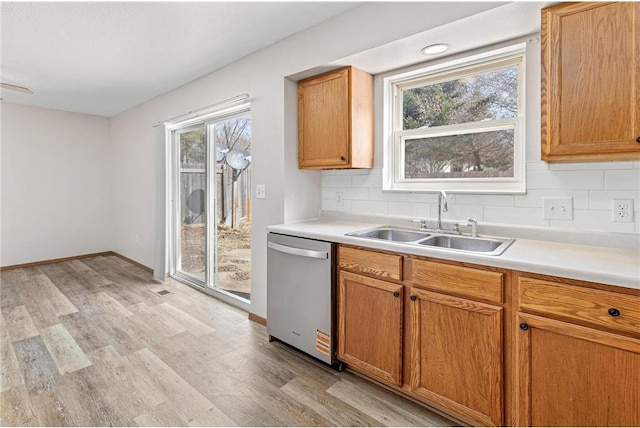 kitchen featuring a sink, decorative backsplash, light countertops, dishwasher, and light wood-type flooring