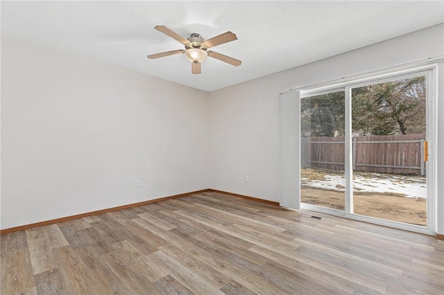 spare room with wood finished floors, visible vents, baseboards, ceiling fan, and a textured ceiling