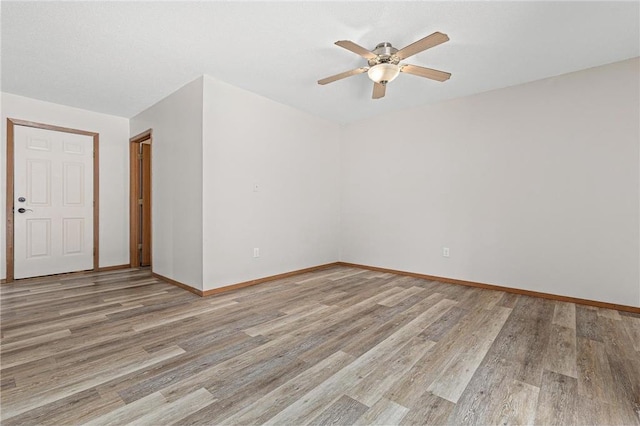 spare room featuring light wood finished floors, baseboards, and a ceiling fan