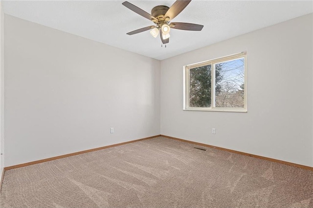 carpeted empty room featuring visible vents, baseboards, and ceiling fan