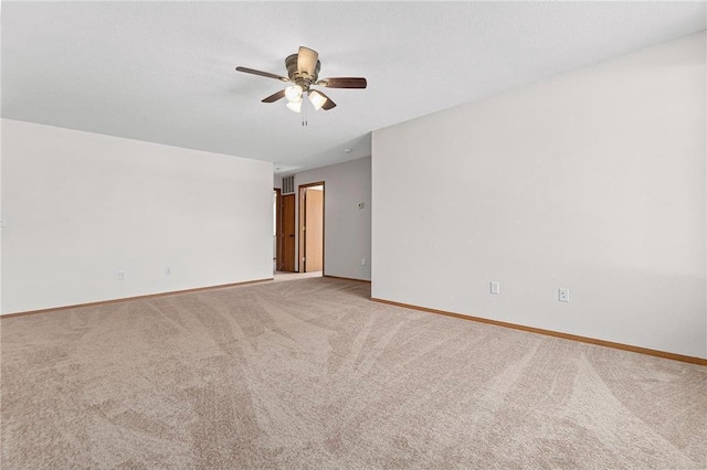 carpeted spare room featuring visible vents, baseboards, and ceiling fan