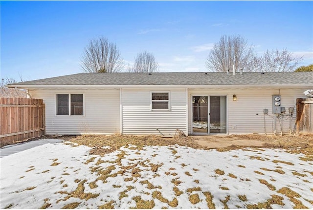 back of house featuring fence and a shingled roof