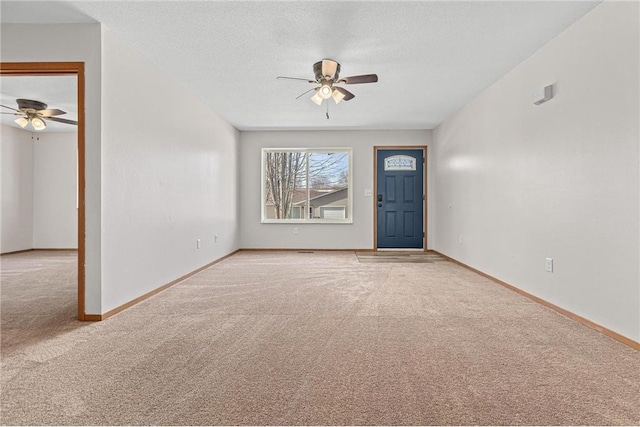 entryway with ceiling fan, baseboards, carpet floors, and a textured ceiling